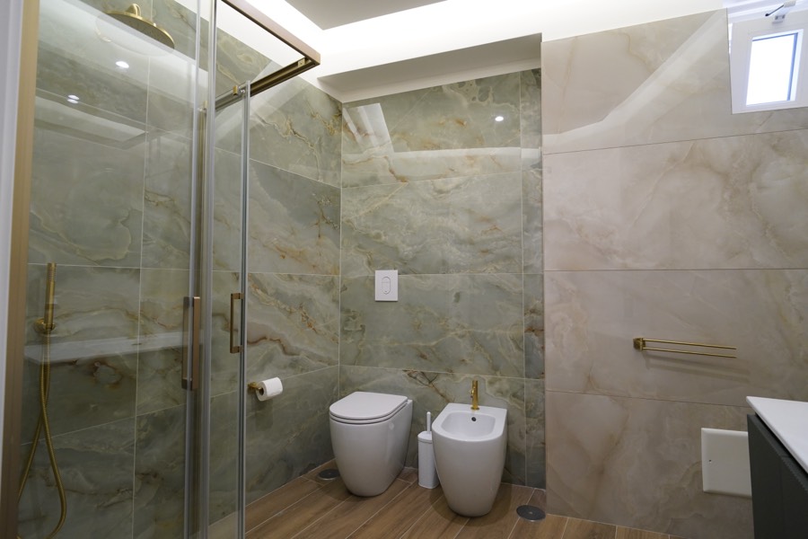 Bagno privato della Camera Camelia in marmo con doccia e rubinetteria dorata