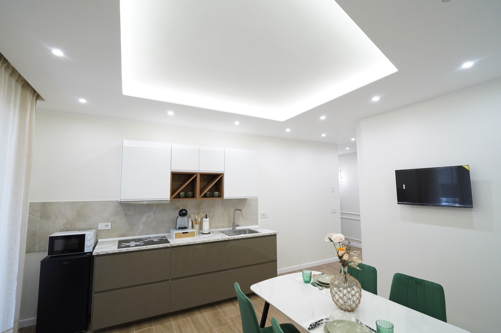 Cucina e zona pranzo di Imarè con TV a parete e illuminazione a soffitto