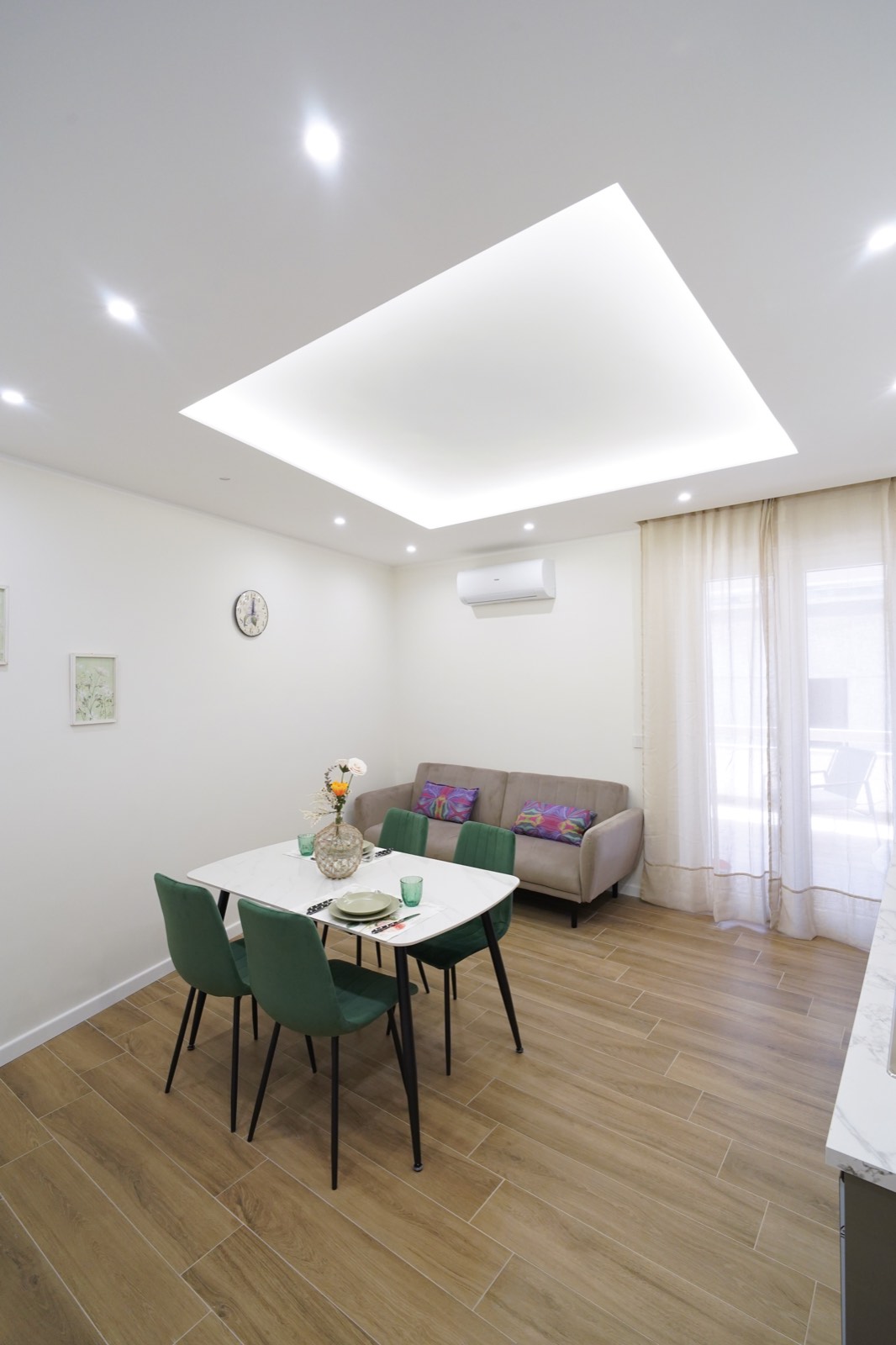 Zona living condivisa di Imarè con tavolo da pranzo, sedie in velluto verde e divano